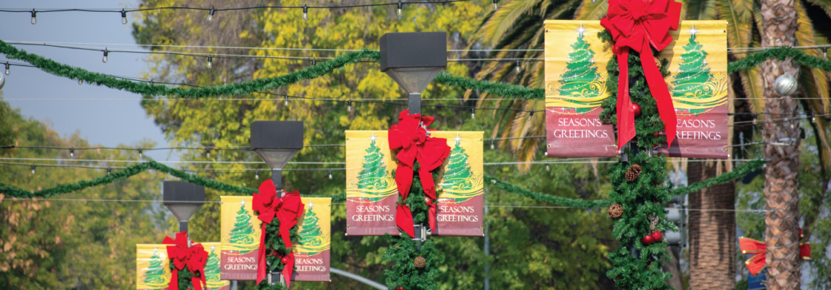 double banner with red Christmas bow hanging on street lights